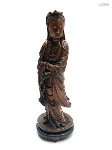 A Chinese carved wood figure of the Goddess Guanyin, holding a set of prayer beads in her left hand,