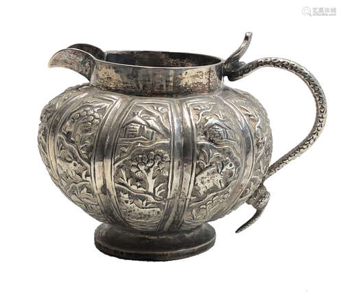 A Chinese silver jug, 19th century, the fluted body decorated with trees, pagodas,