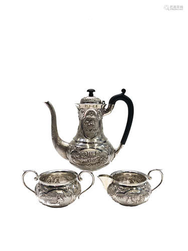 An Indian silver coffee pot with matching milk jug and sugar bowl each repousse decorated and