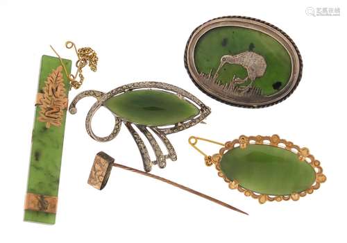 Four jade brooches one with unmarked gold mount and a silver kiwi example, the largest 5.5cm in