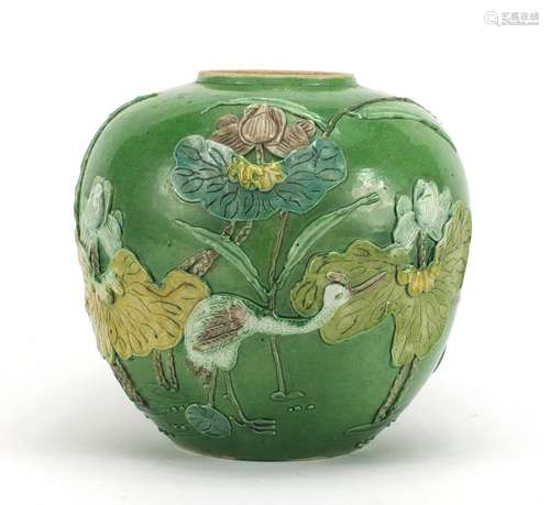 Chinese porcelain green glazed jar, decorated in relief with a craned amongst flowers and reeds,