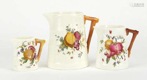 Graduated set of three Royal Worcester naturalistic jugs, hand painted with fruits, each with