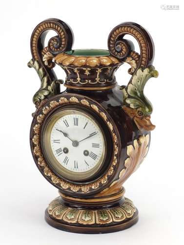 Continental pottery mantel clock in the form of vase with twin dolphin handles, the enamelled dial