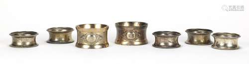 Set of five circular silver napkin rings and a pair of silver coloured metal napkin rings,