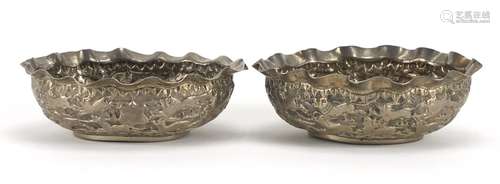 Pair of Indian unmarked silver bowls, each embossed with lions chasing antelope, each 12cm wide,