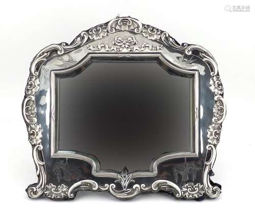 Large silver easel mirror with bevelled glass and embossed with shells and swags, indistinct