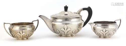 Arts & Crafts style silver three piece tea service embossed with stylised motifs, the teapot with