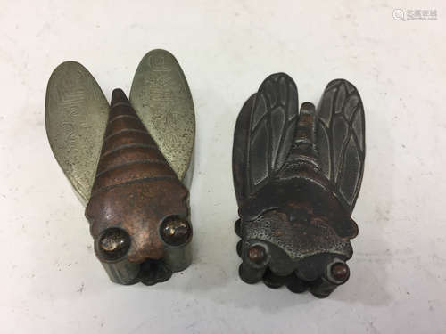 Two metal cicadas, marked.