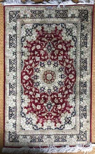 A fine Persian part silk red ground rug centred by a floral design, signed/dated