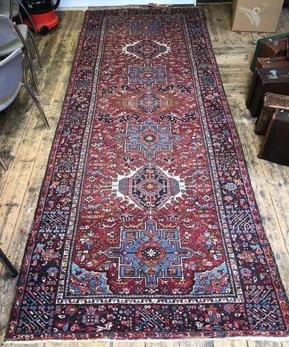 An old Persian Heriz runner, the red ground with seven lozenge pole design