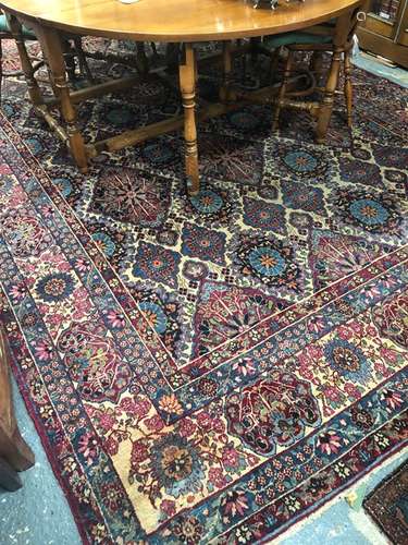 A large old Persian Kirman carpet, the repeating floral lozenge design on camel ground