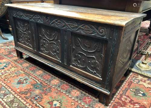 A 17th/18th century oak coffer, the two plank top over a joint framed triple panel front relief carv