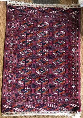 A small Turkmen design rug, the mid-red ground with two rows of guls