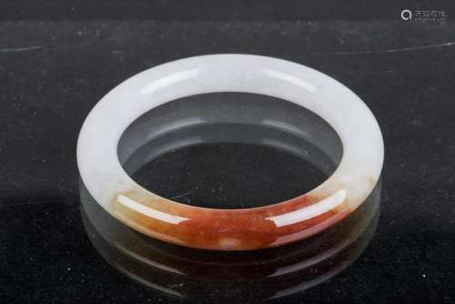 A JADE BANGLE OF VARIEGATED WHITE AND BROWNISH ORANGE,