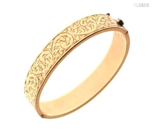 Yellow metal snap bangle with foliate scroll engraved decoration, stamped '9ct Gold Metal Core',