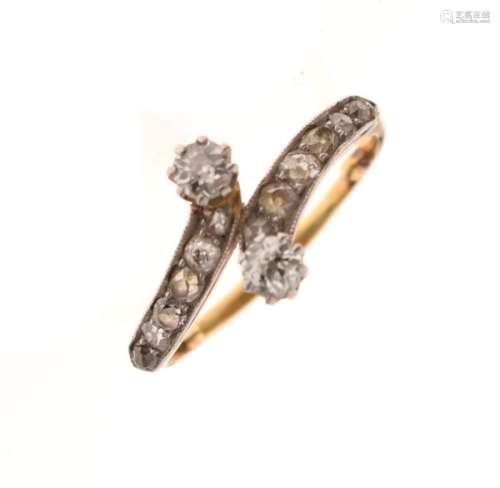 Unmarked yellow metal and diamond ring of crossover design and set two larger stones and ten