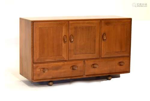 Ercol 'Golden Dawn' elm sideboard fitted three cupboard doors over two drawers on castors, 129cm