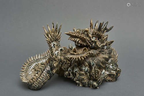 A ceramic figure of a dragon resting on its claws  and a wide open mouth and inlayed eyes