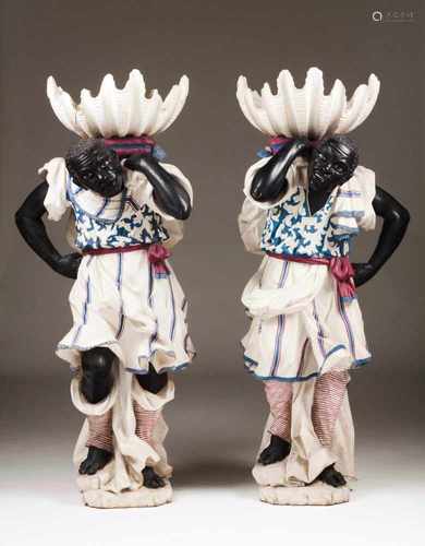 A pair of BlackamoorsCarved and polychrome wooden figures holding shell shaped basinsItaly, 18th