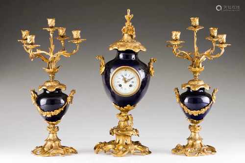 A garnitureTable clock and pair of five branch candelabraGilt bronze and porcelainUrn shaped clock