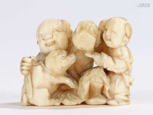 Japanese Meiji period ivory netsuke, carved as a father and child playing with a puppy, 4cm wide