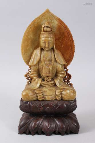 A GOOD EARLY 20TH CENTURY CHINESE CARVED SOAPSTONE FIGURE OF GUANYIN, seated upon a separate