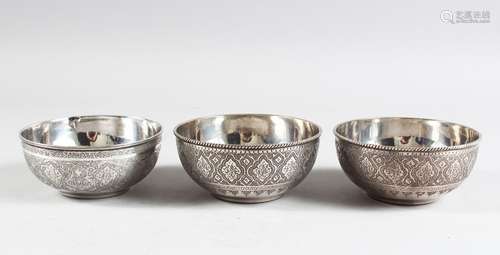 THREE PERSIAN WHITE METAL CIRCULAR BOWLS with chased borders, 10cm diameters.