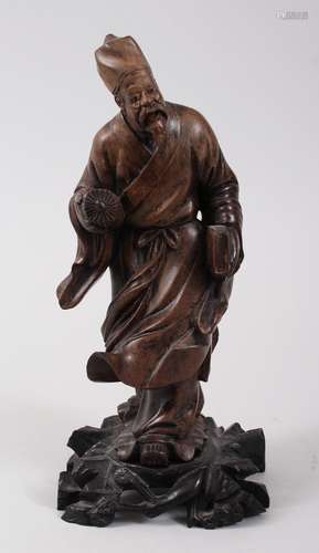 A 19TH CENTURY CHINESE HARDWOOD CARVED FIGURE OF A SAGE, modeled holding a book other item, fixed to