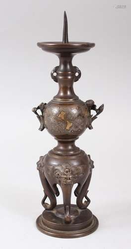 A JAPANESE MEIJI PERIOD BRONZE AND MIXED METAL CANDLE STICK, stood on three shi shi head legs, the