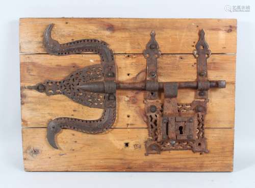 A 17TH CENTURY INDO PORTUGUESE IRON LOCK on a wooden block, 52cm long.