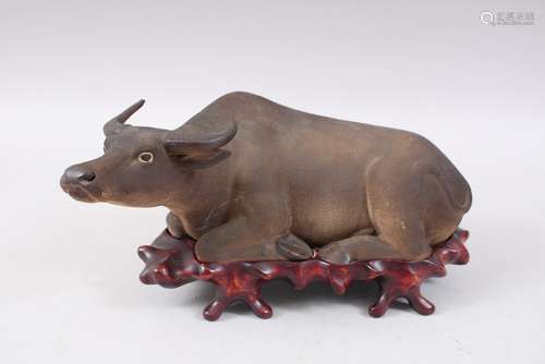 AN ORIENTAL POTTERY FIGURE OF A RECUMBENT OXEN, the oxen realistically rendered, the base with an