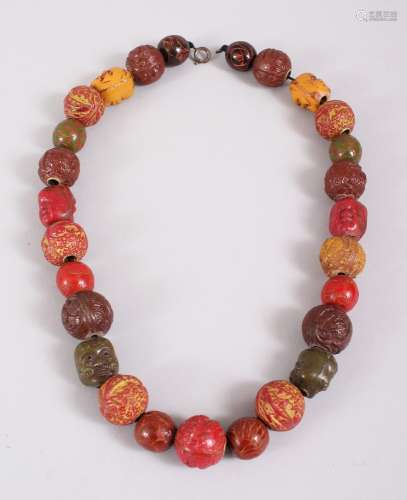 A JAPANESE CARVED & STAINED TAGUA NUT OJIME BEAD NECKLACE, consisting of 27 beads, 48.5cm long,