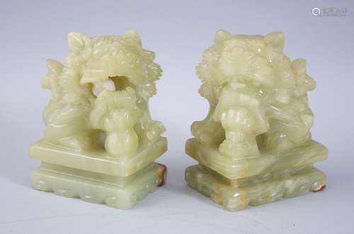 A PAIR OF 20TH CENTURY CHINESE JADE / JADELIKE HARDSTONE LION DOGS, both sat upon carved pedestal