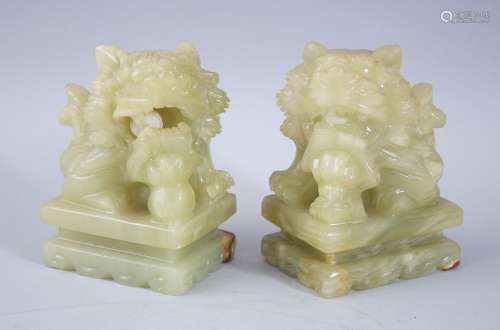 A PAIR OF 20TH CENTURY CHINESE JADE / JADELIKE HARDSTONE LION DOGS, both sat upon carved pedestal
