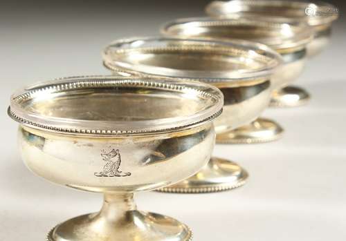 A SET OF FOUR GEORGE III OVAL PEDESTAL SALTS, with beaded edges and glass liners.