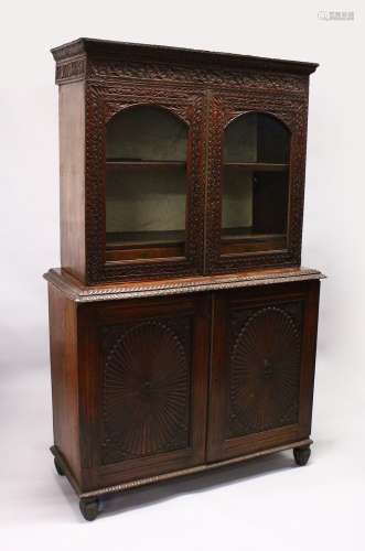 A GOOD 19TH CENTURY ANGLO INDIAN PADAUK WOOD CUPBOARD BOOKCASE, with floral carved cornice, a pair
