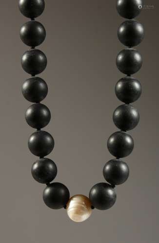 A HEAVY BLACK BEAD NECKLACE with a single pearl.