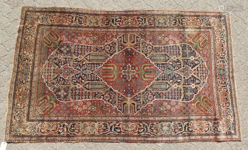 A PERSIAN KASHAN KORK WOOL RUG with a large central motif in red and blue.