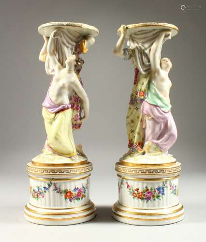 A PAIR OF RUSSIAN PORCELAIN STANDS with circular tops and bases, held by two female figures and