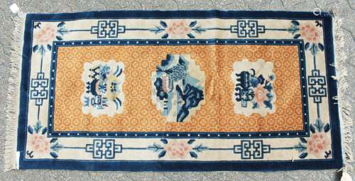 A CHINESE WOOL RUG with three motifs, orange ground with blue and white border. 4ft 6ins x 2ft