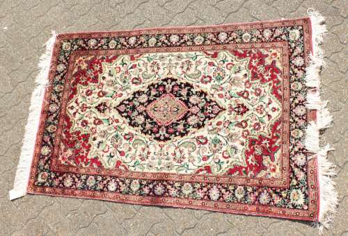 A FINE PERSIAN QUM SILK RUG with a central oval motif on a cream and blue background and floral