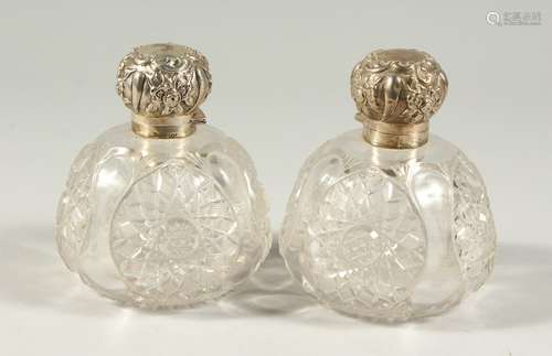 A PAIR OF VICTORIAN CUT GLASS GLOBULAR SCENT BOTTLES with silver repousse tops. 4INS DIAMETER.