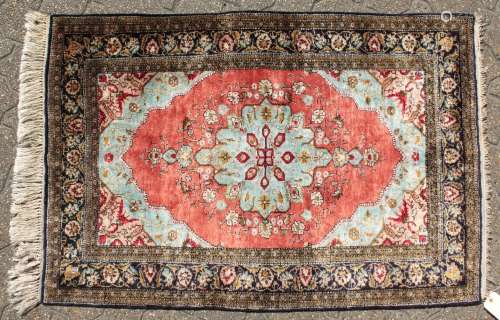 A FINE PERSIAN SILK RUG with central motif on a red background and floral border. 4ft 2ins x 2ft
