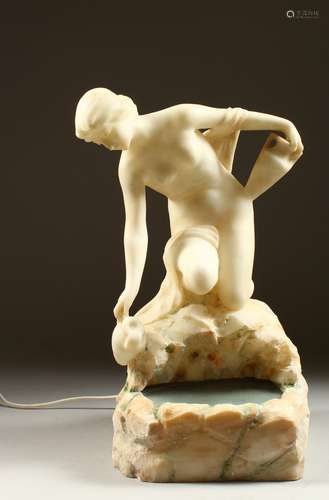 AN UNUSUAL CARVED ALABASTER ILLUMINATED FIGURE, modelled as a seated female nude gathering water