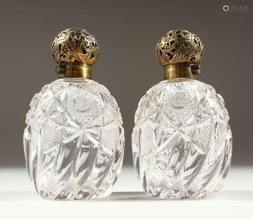 A SUPERB PAIR OF VICTORIAN CUT GLASS CRYSTAL SCENT BOTTLES AND STOPPERS with pierced silver tops.