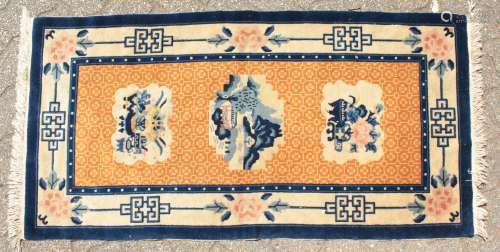 A CHINESE WOOL RUG with three main motifs with blue and green border. 4ft 7ins x 2ft 3ins.