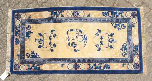 A CHINESE WOOL RUG with three central motifs in blue and cream. 4ft 7ins x 2ft 3ins.