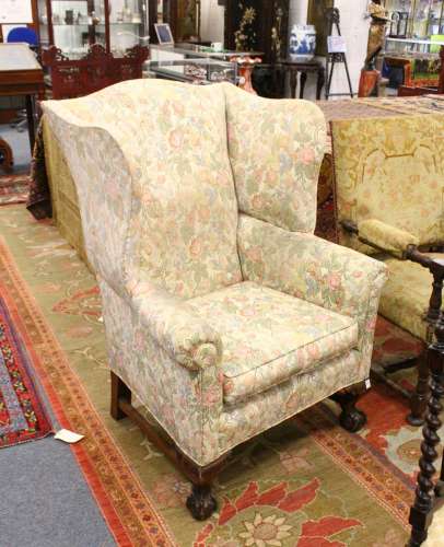 AN WALNUT WING ARMCHAIR on cabriole legs, with claw and ball feet.