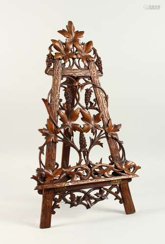 A GOOD 19TH CENTURY BLACK FOREST CARVED WOOD PIERCED EASEL. 66cms high, carved with fruiting vines.