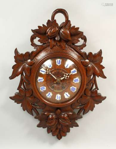 A CARVED OAK BLACK FOREST STYLE WALL CLOCK, with leaf carved decoration and enamel numerals. 64cms